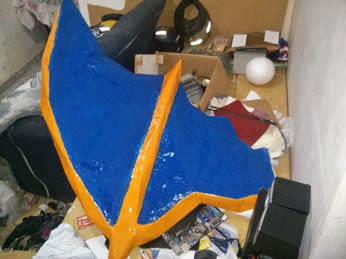 A wing membrane painted blue and orange, drying on the workshop floor.