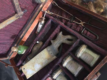 Angled view of the case with the bone saw and modified instruments in their compartments.