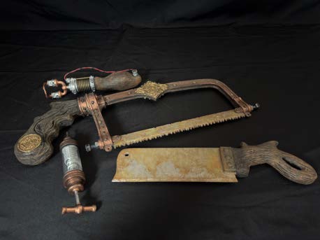 Bone saw, faux cleaver and smaller surgical instruments arranged together on a black background.