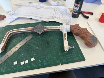 Laser-cut timber and acrylic prop components laid out on a cutting mat before assembly.