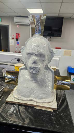The bust armature and base set up on the workshop bench before clay is applied.