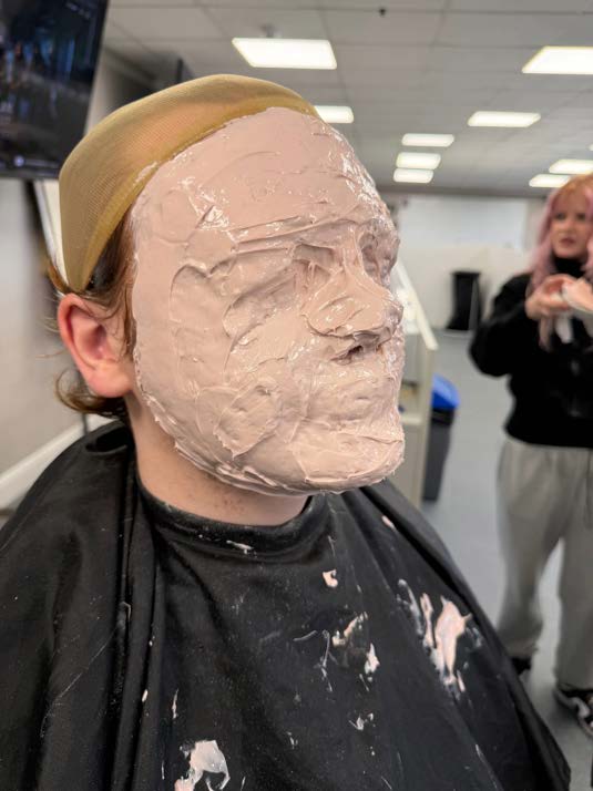 A lifecast bandage shell being taken from a model's face during training.